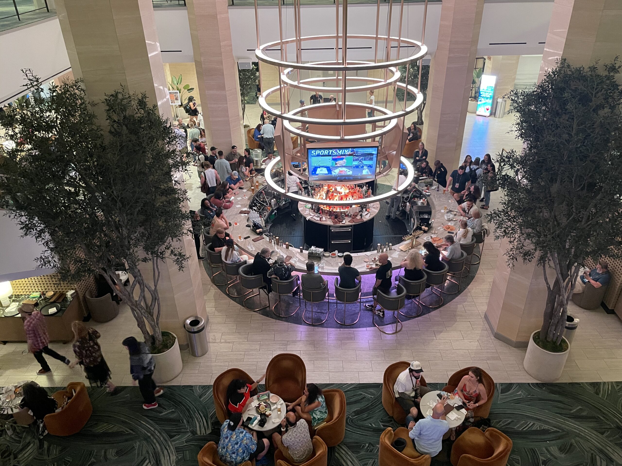 View from above of a circular hotel bar with additional seating, full of people chatting.